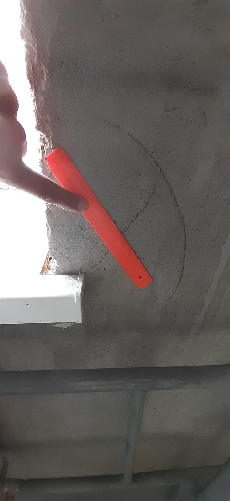 Осмотр участка стены у окна кладовки с отмеченным дефектом поверхности
